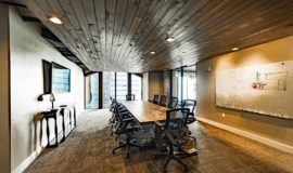 Conference room with stone table, floor to ceiling windows and rich wood ceiling.