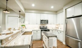 Kitchen with stainless steel gas range and microwave, tiled backsplash, and smooth countertops.