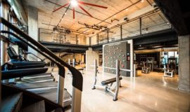Fitness center with weight benches, treadmills, stair stepper, and rotating rock climbing wall.