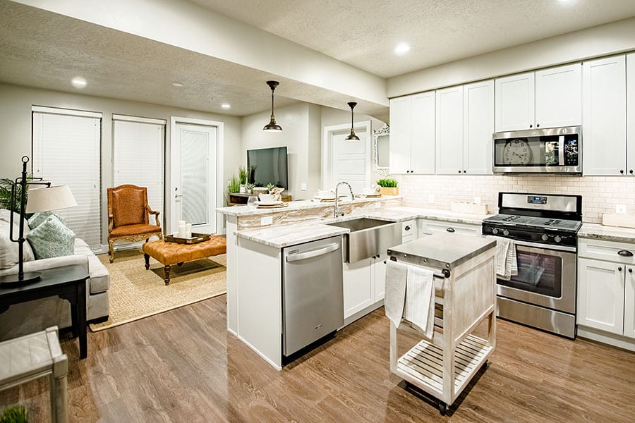 Kitchen and living space with wood floors, stainless steel appliances, and smooth countertops.