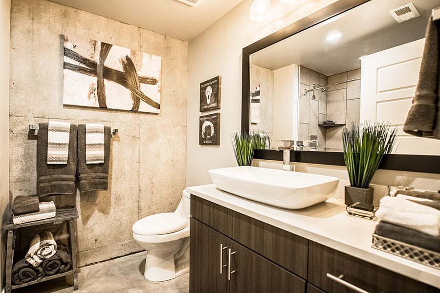 Bathroom with wood cabinets, polished concrete floors, and countertop sink.