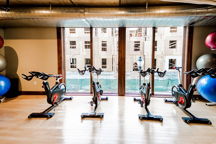 Fitness center with wood floors, four spin bicylces, and floor to ceiling windows.