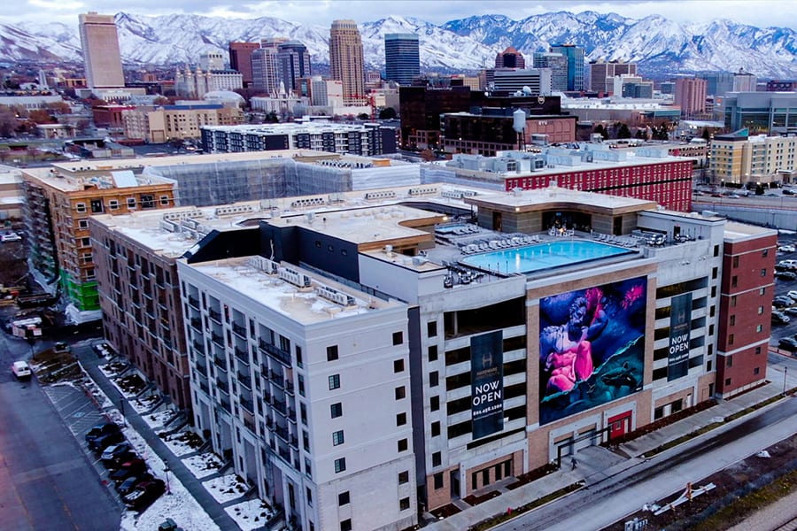 Aerial view of Hardware District with Salt Lake City skyline and Wasatch Mountains in the distance.