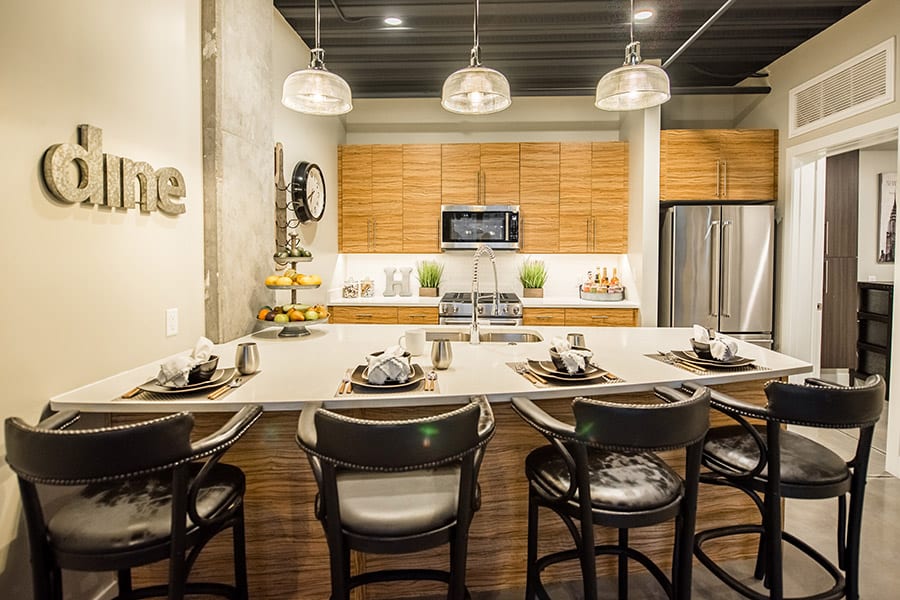 Kitchen with wooden cabinets, a tall breakfast bar with stools, and polished concrete floors.