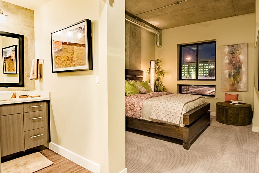 Master bedroom and bathroom with wood drawers, wood platform bed, and city facing square window.
